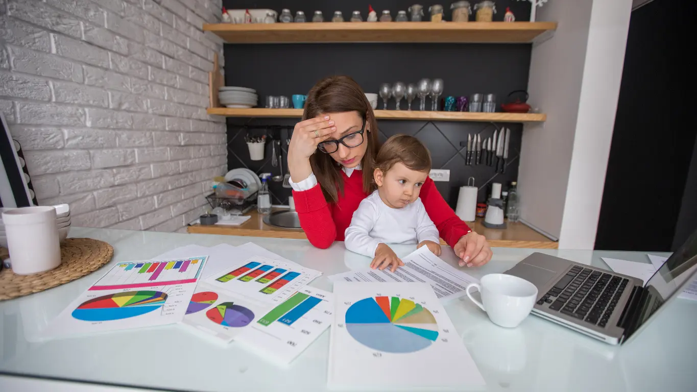 Madre intentando trabajar desde casa mientras cuida a su hijo, reflejando el estrés del equilibrio entre vida laboral y familiar que el programa Oxigénate aborda.