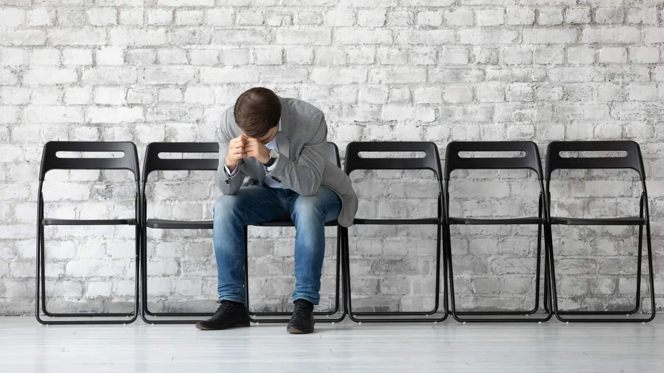 Candidato mayor de 40 años, esperando ansioso antes de una entrevista de trabajo, reflejando la incertidumbre sobre cómo destacar sus habilidades y obtener el empleo deseado.