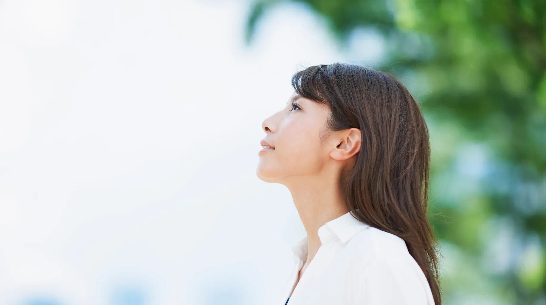 Mujer mirando hacia el cielo con expresión serena y esperanzadora, evocando la búsqueda de sentido y transformación personal